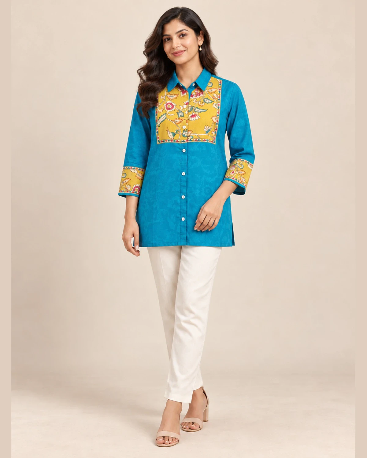 Woman wearing a turquoise shirt kurti with a mustard floral yoke and cream trousers