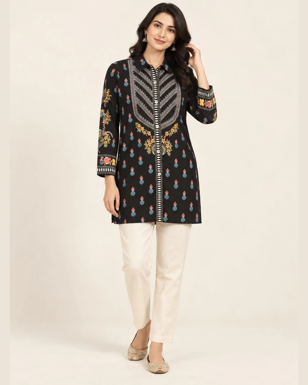 Woman wearing a black motif print shirt kurti with a chevron panel and cream trousers