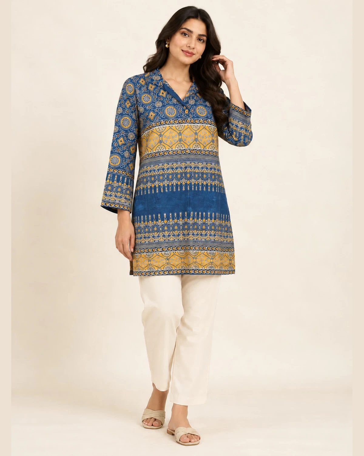 Woman wearing a blue and ochre border print shirt kurti with cream trousers