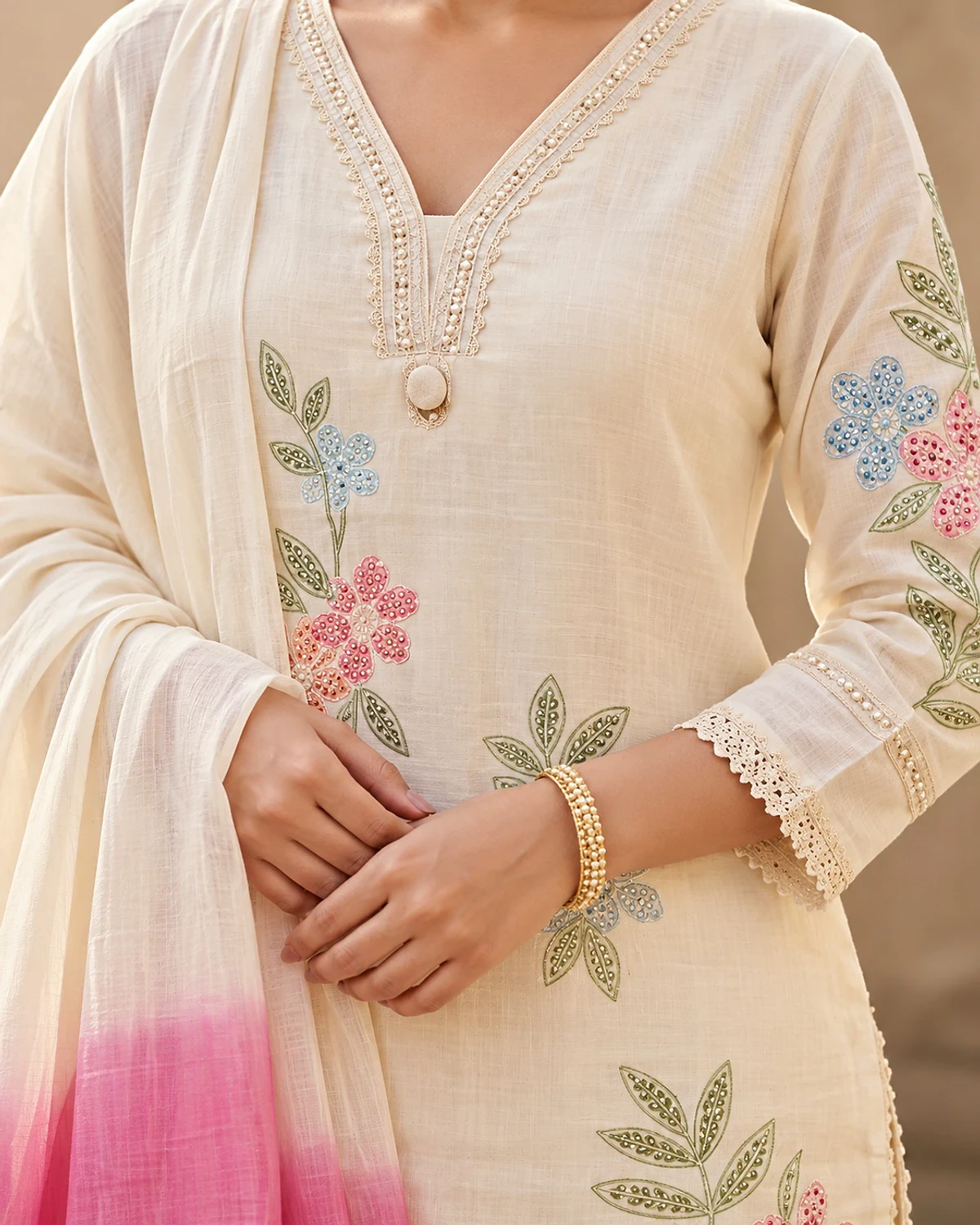 Close-up of the ivory kurta, showing pastel floral motifs and a pink ombre dupatta