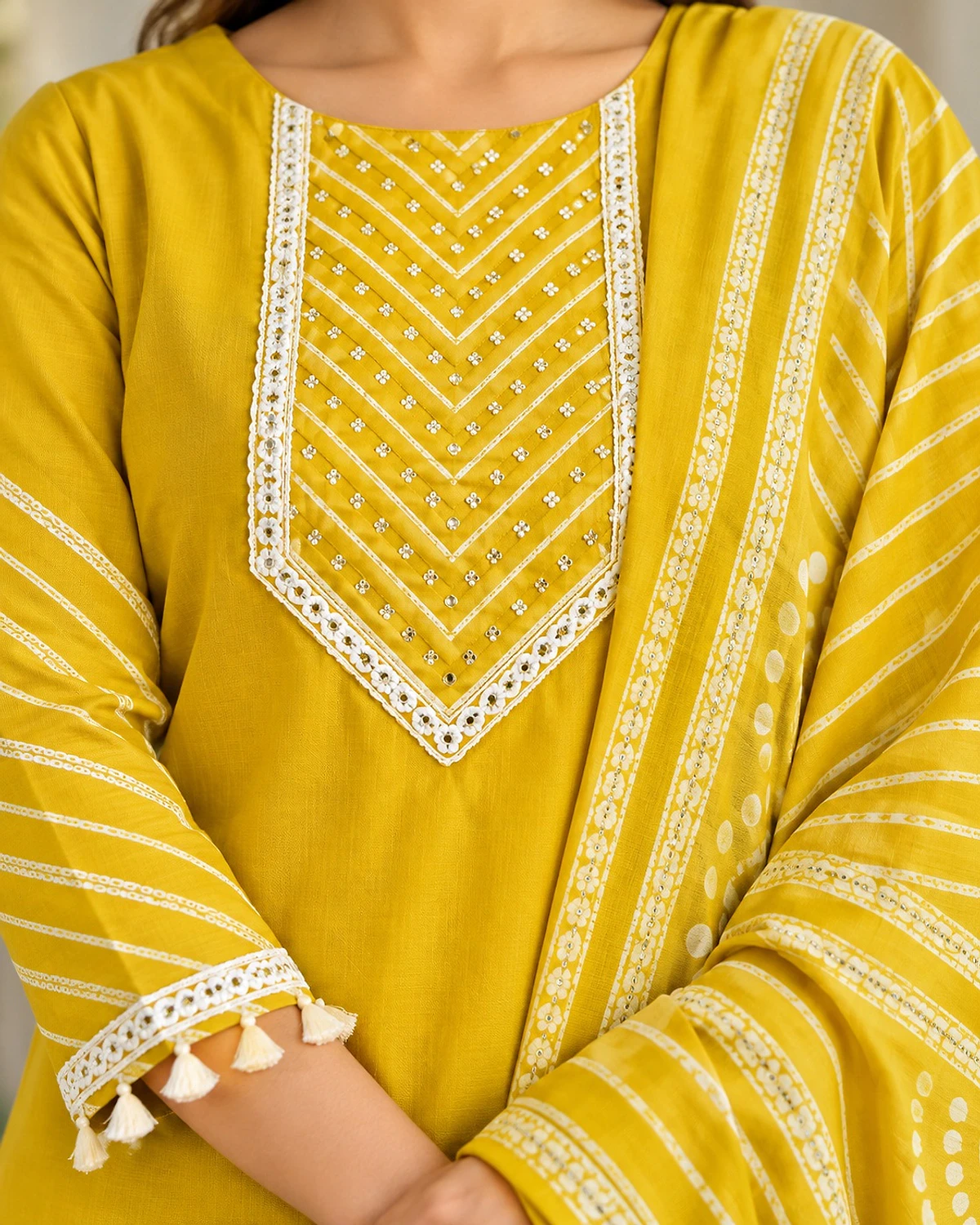 Close-up of the yellow kurta, showing a lace yoke and tassel hem