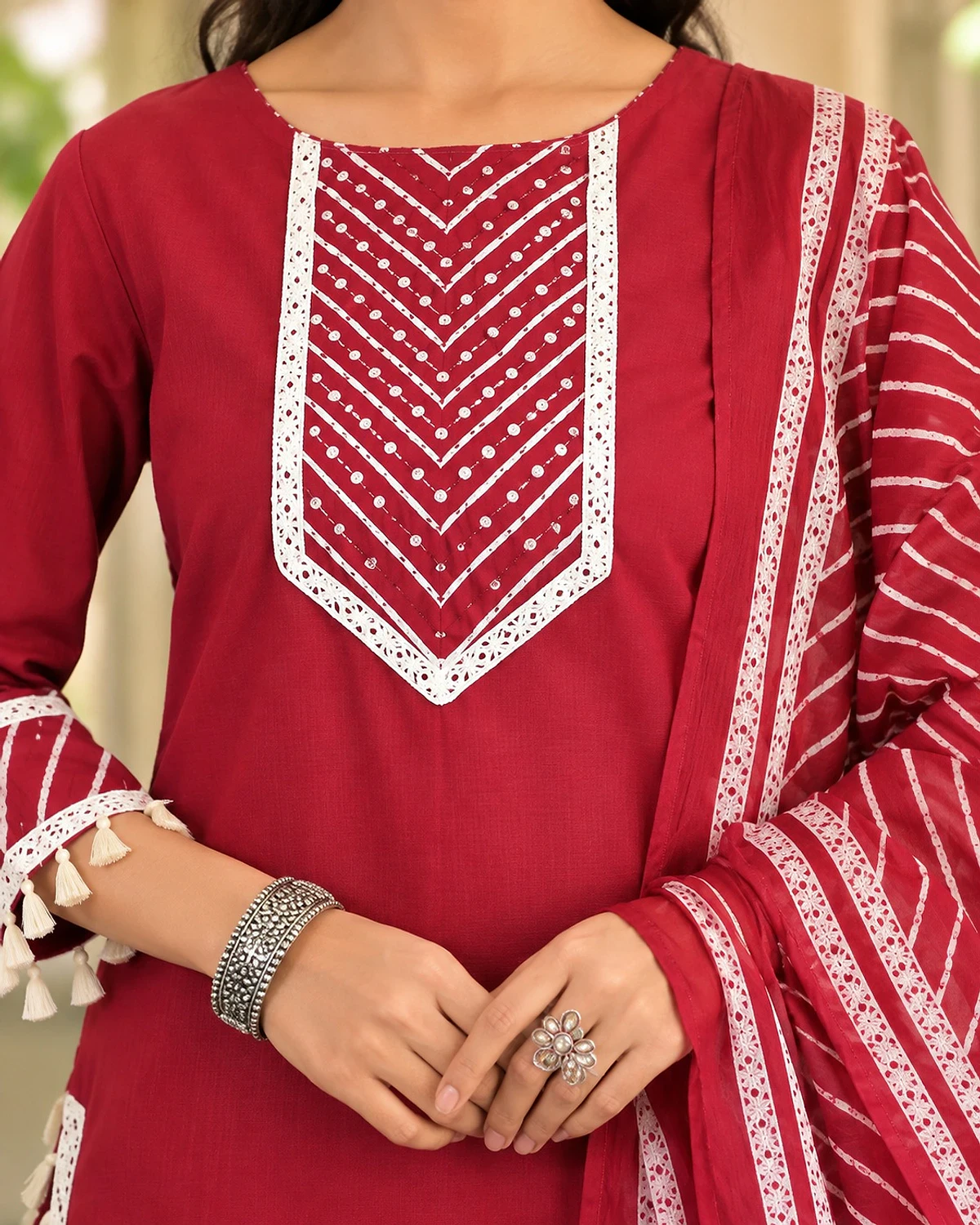 Close-up of the maroon red kurta, showing a lace yoke and tassel hem