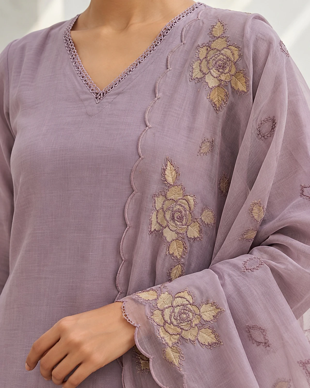 Close-up of the mauve kurta, showing beige rose motifs and a scalloped panel