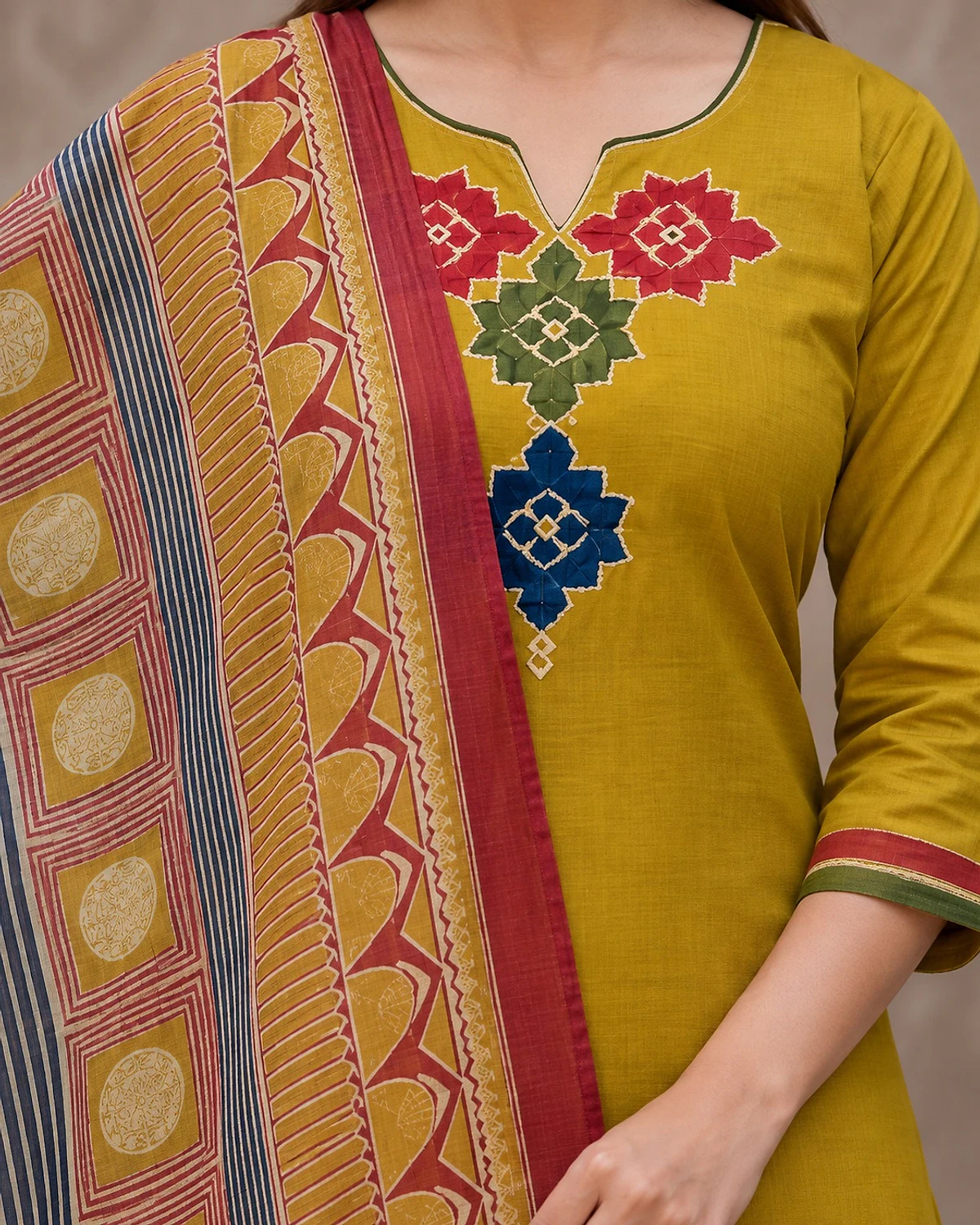Close-up of the mustard kurta, showing geometric motifs at the neck