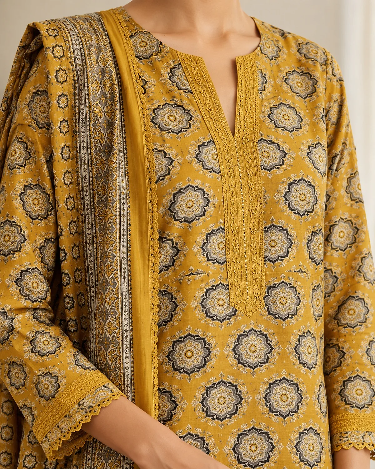 Close-up of the mustard kurta, showing an all-over medallion print and lace trims