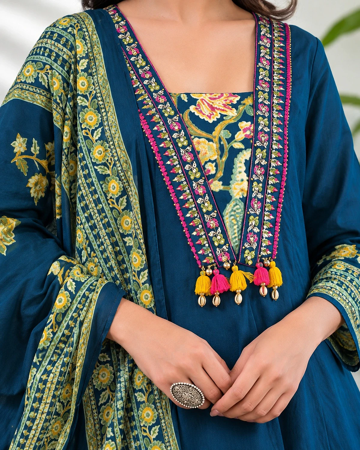 Close-up of the teal blue kurta, showing floral printed borders and colourful tassels