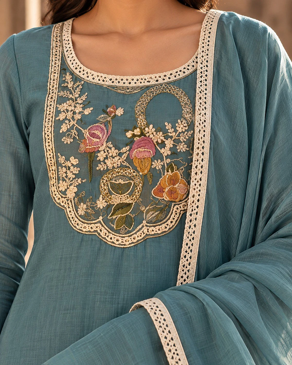 Close-up of the turquoise kurta, showing a floral yoke edged in lace