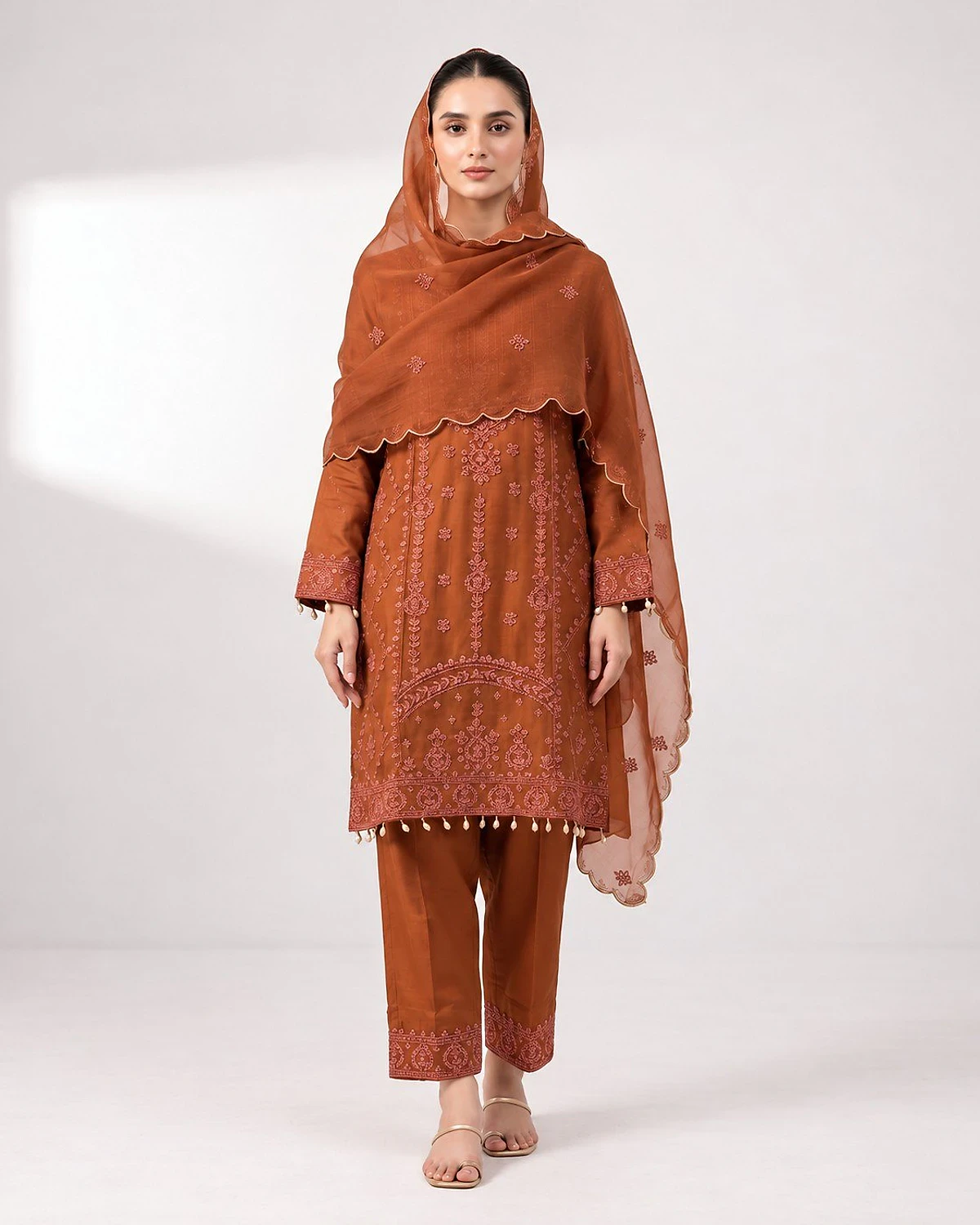 Woman wearing a rust kurta, trousers and dupatta