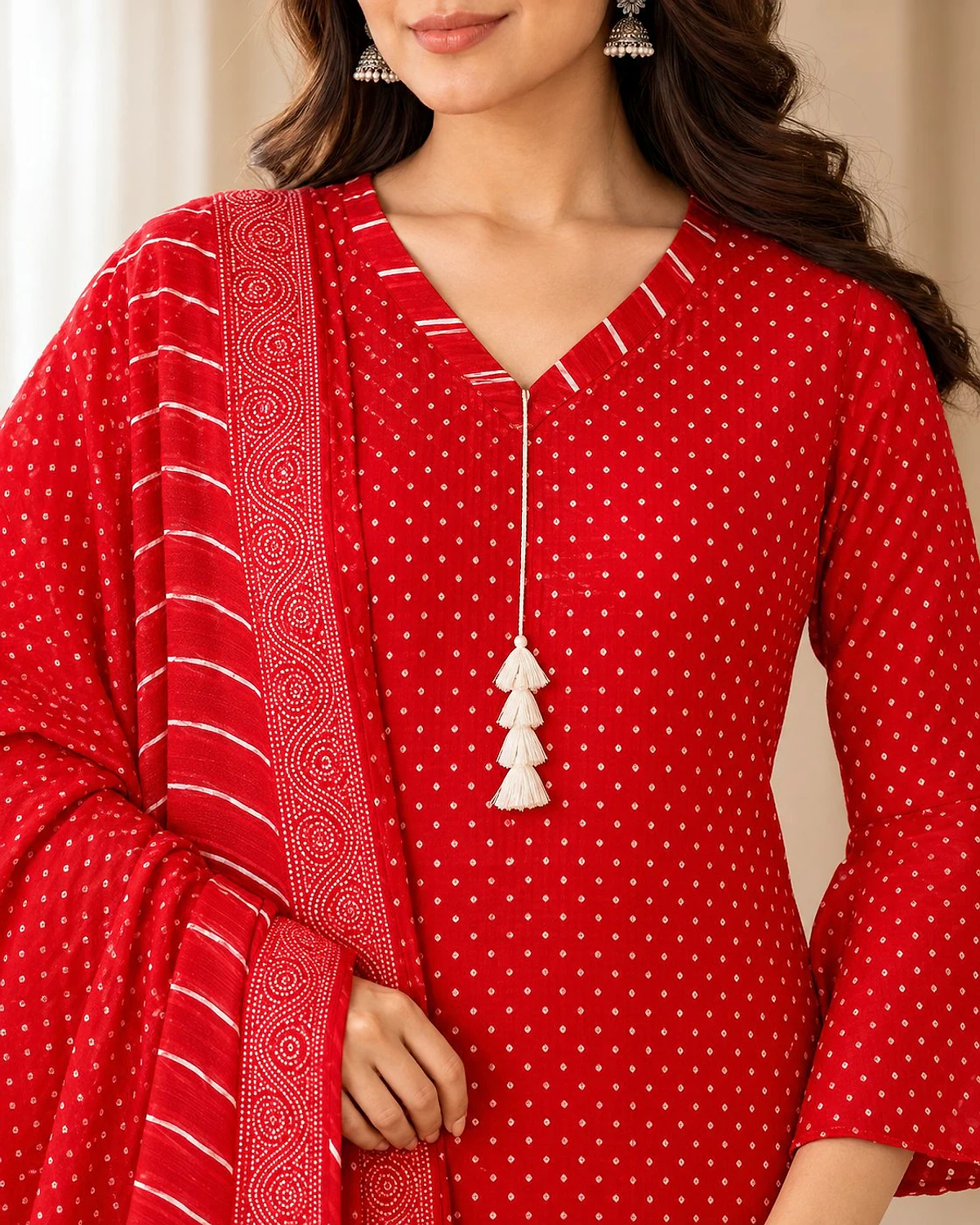 Close-up of the red kurta, showing a fine dot print and a tasselled neck tie