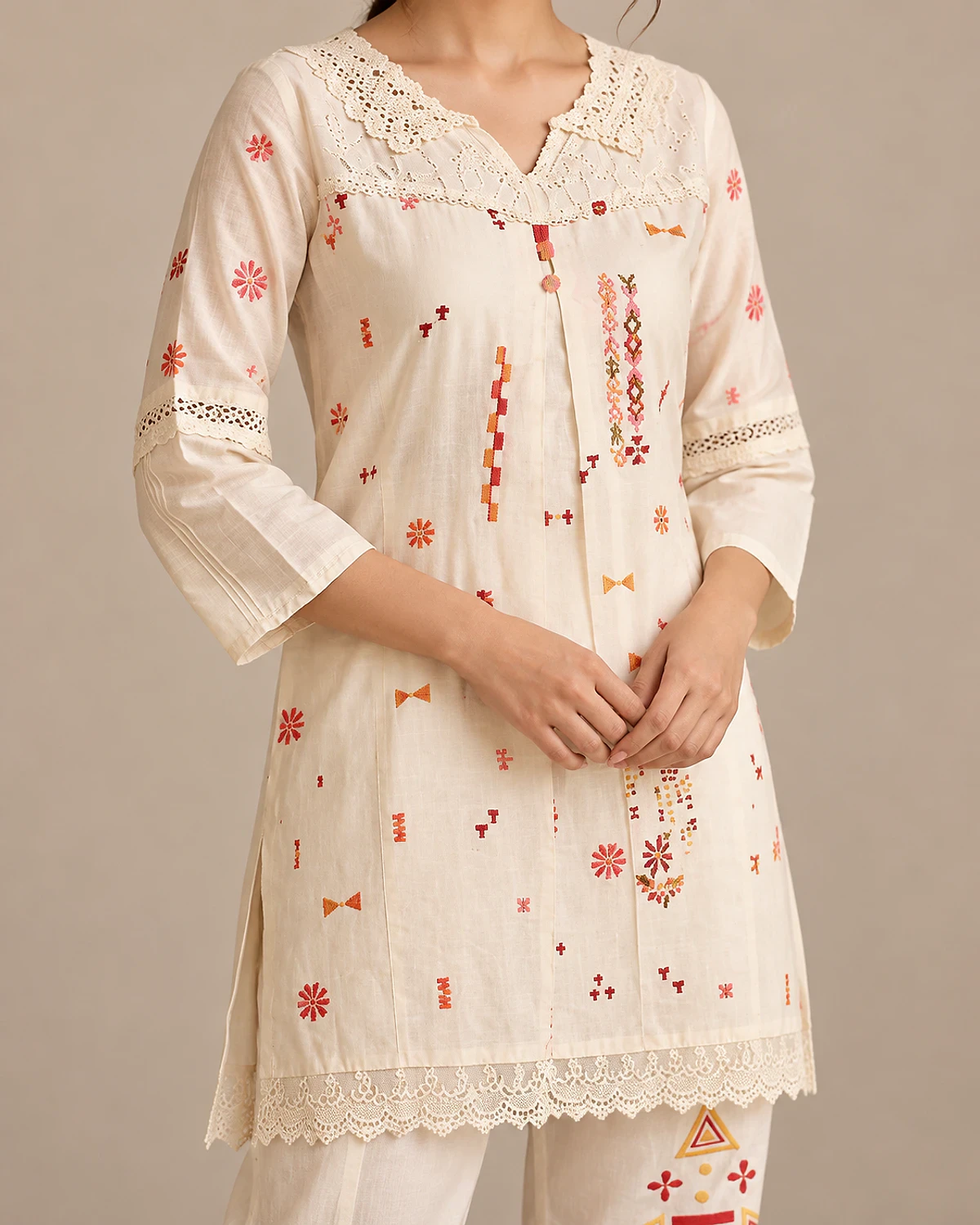 Close-up of the ivory tunic's lace yoke and small motifs