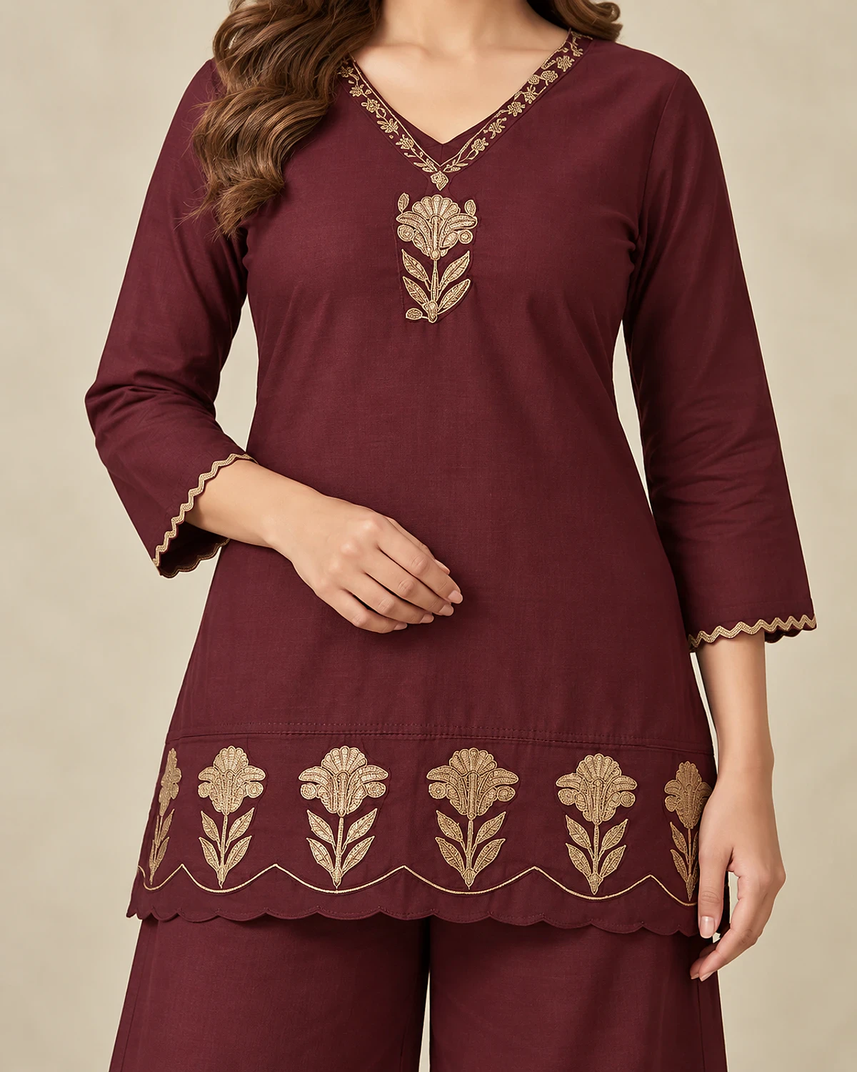 Close-up of the maroon kurta's gold-tone flower border and scalloped hem