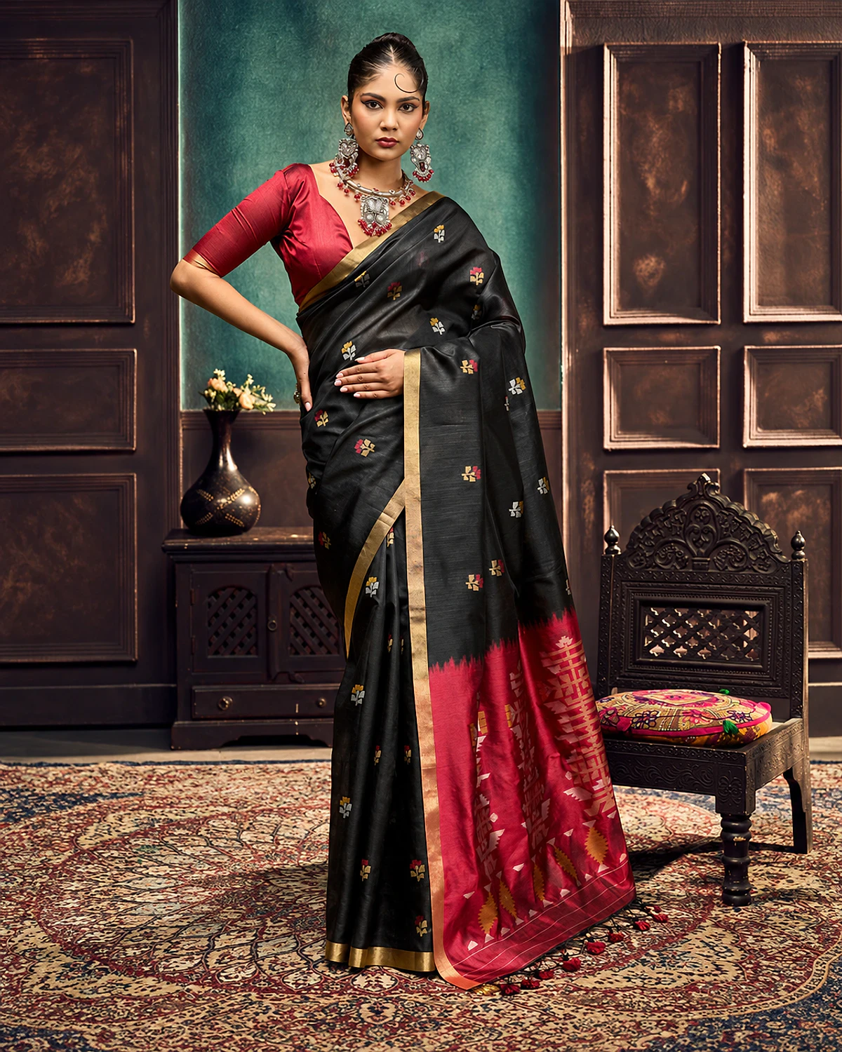 Woman wearing a black Kanoi Paithani tussar silk saree with multicolour butti motifs, a gold-tone border and a red geometric pallu with tassels