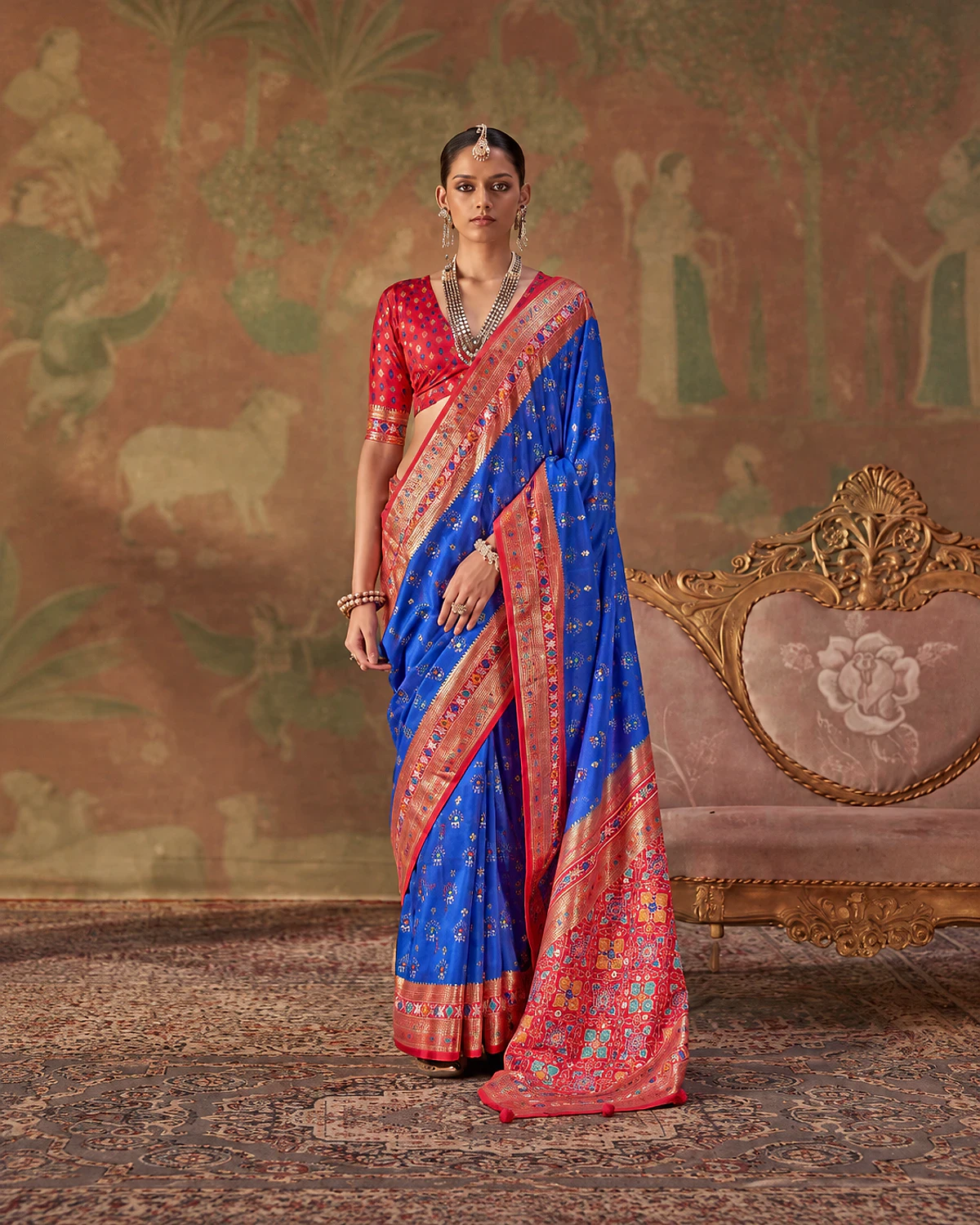 Woman standing in the royal blue Tarini Patola-style sigma silk saree, its red-pink pallu over one shoulder