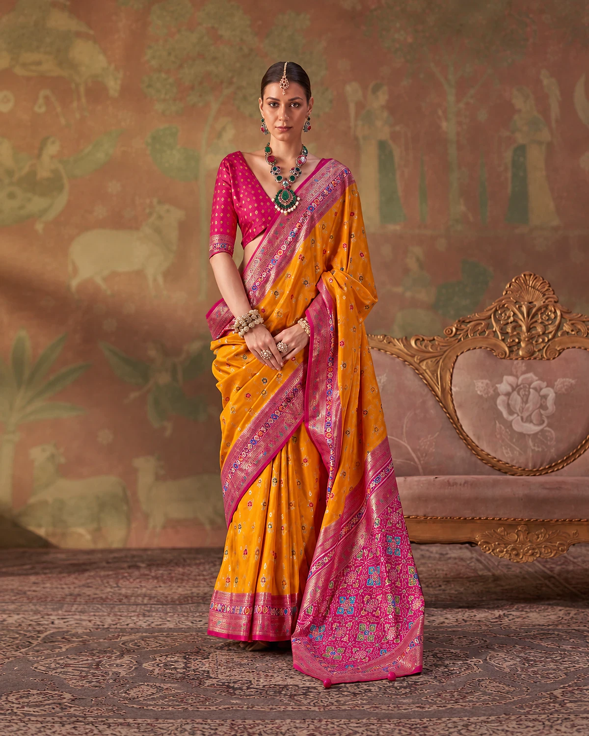 Woman standing in the mustard Tarini Patola-style sigma silk saree, its magenta-pink pallu over one shoulder