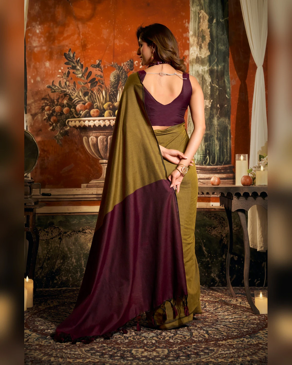 Back view of the olive green mal cotton saree, its maroon pallu falling down the back over a maroon blouse