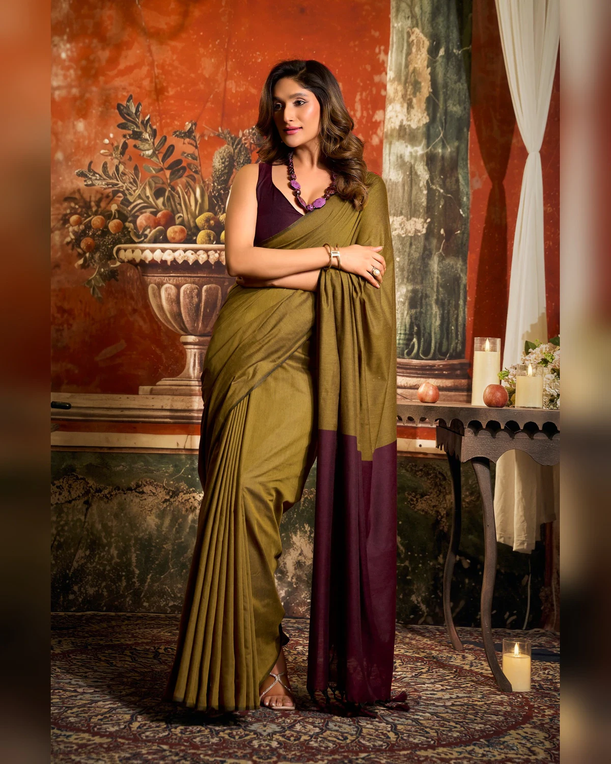 Woman standing in the olive green mal cotton saree, its maroon pallu hanging in front