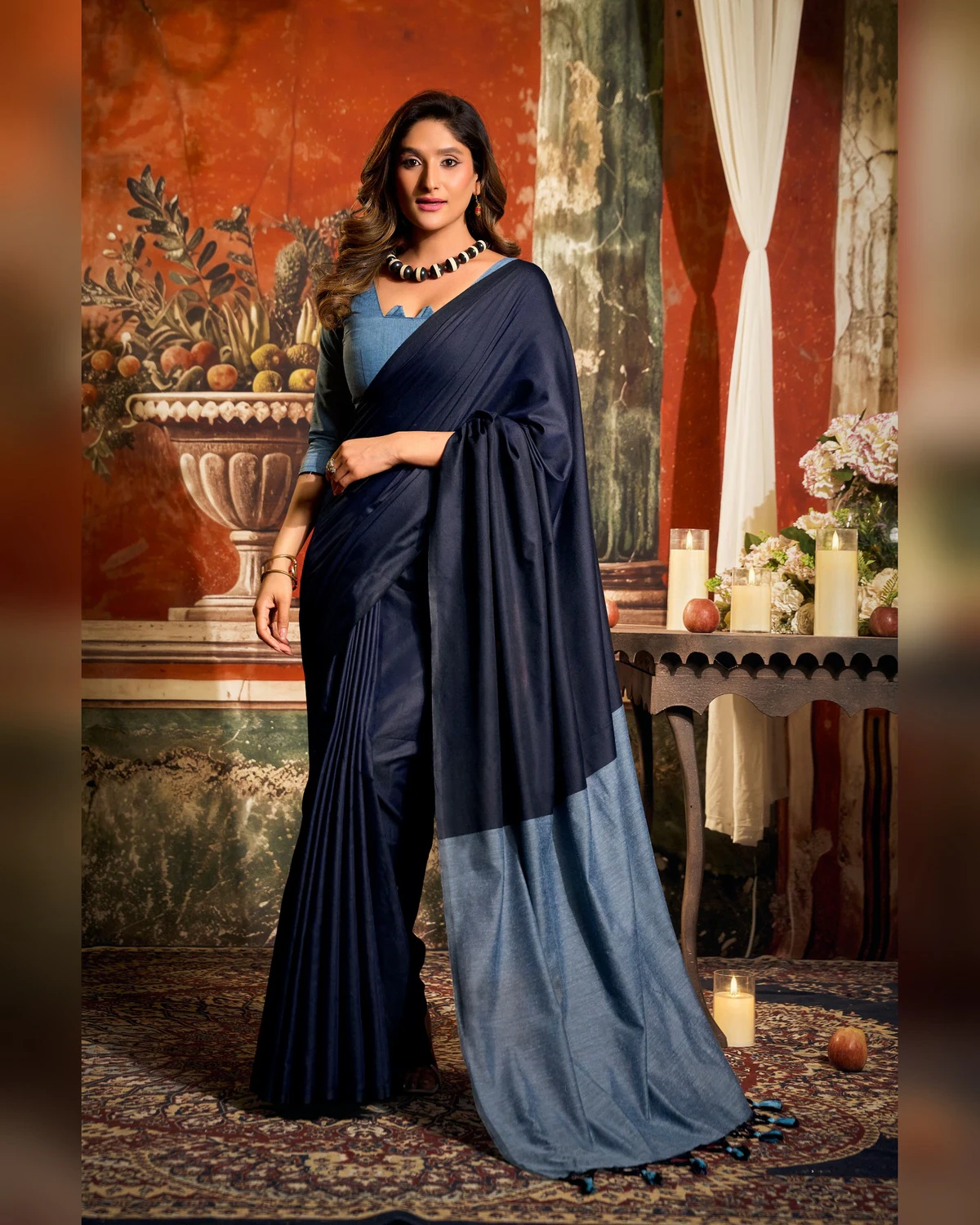Woman standing in the navy blue mal cotton saree, its powder blue pallu falling to the floor