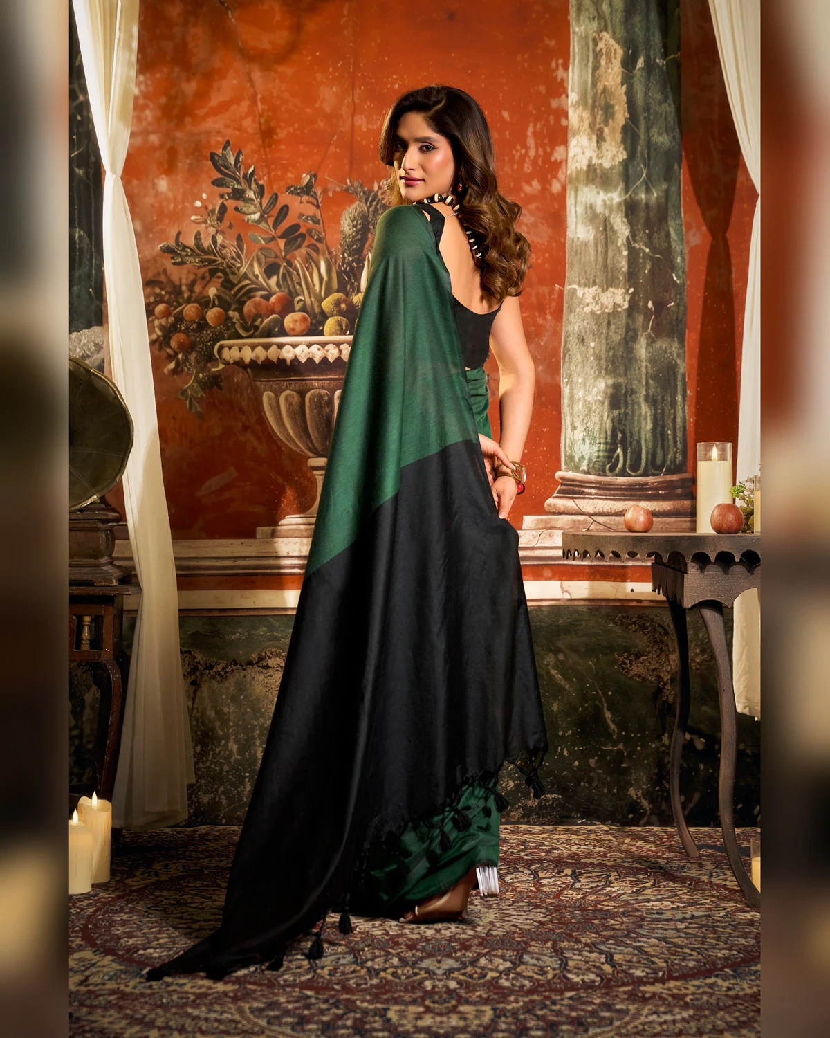 Back view of the bottle green mal cotton saree, its black pallu falling to the floor
