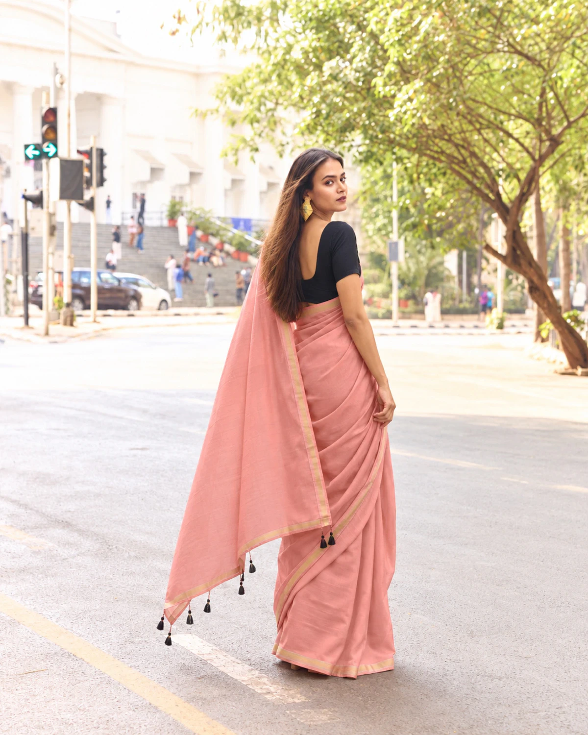 Back view of the dusty pink mul mul cotton saree, its pallu with black tassels held out to the side