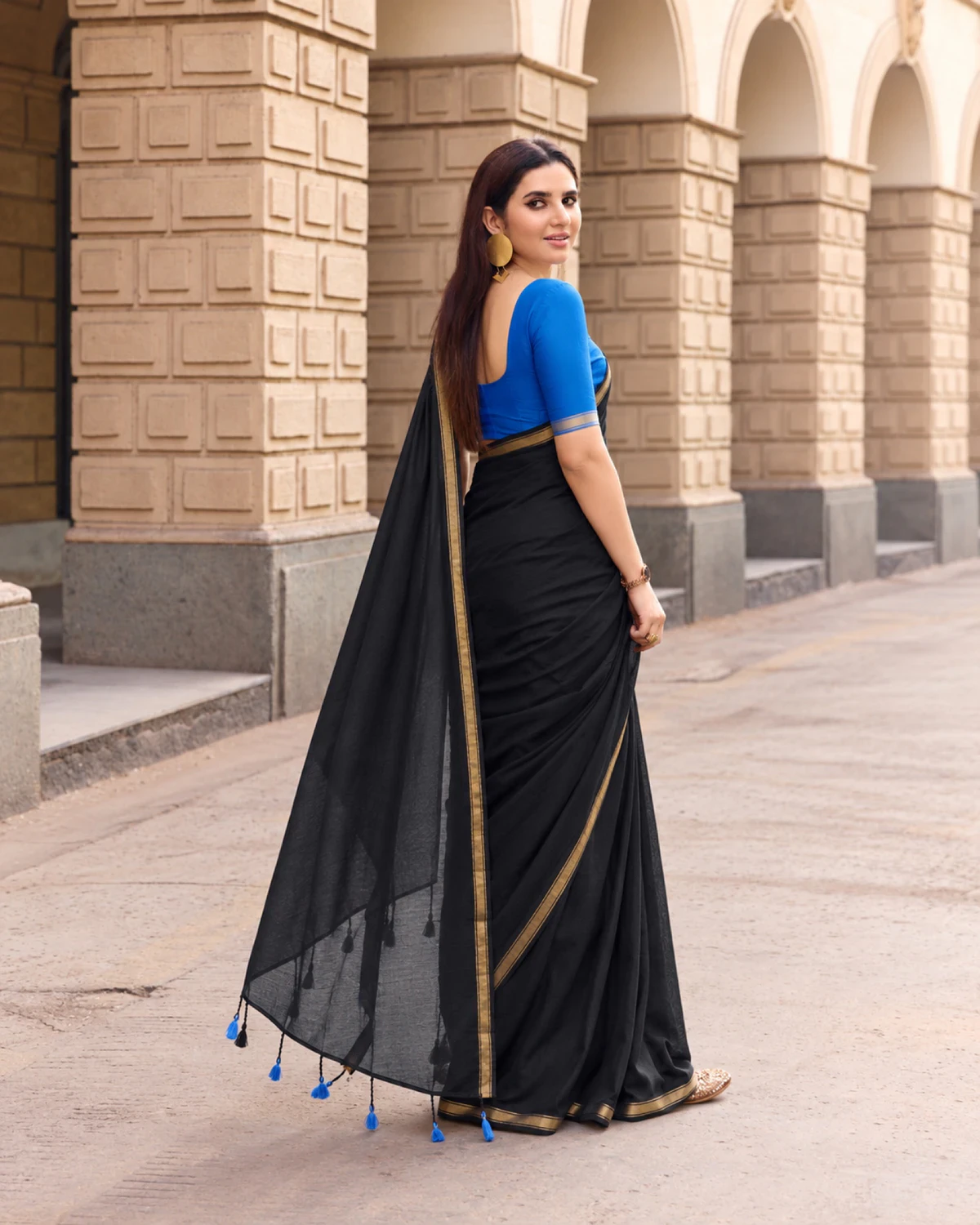 Back view of the black mul mul cotton saree, its pallu with blue tassels falling to the ground