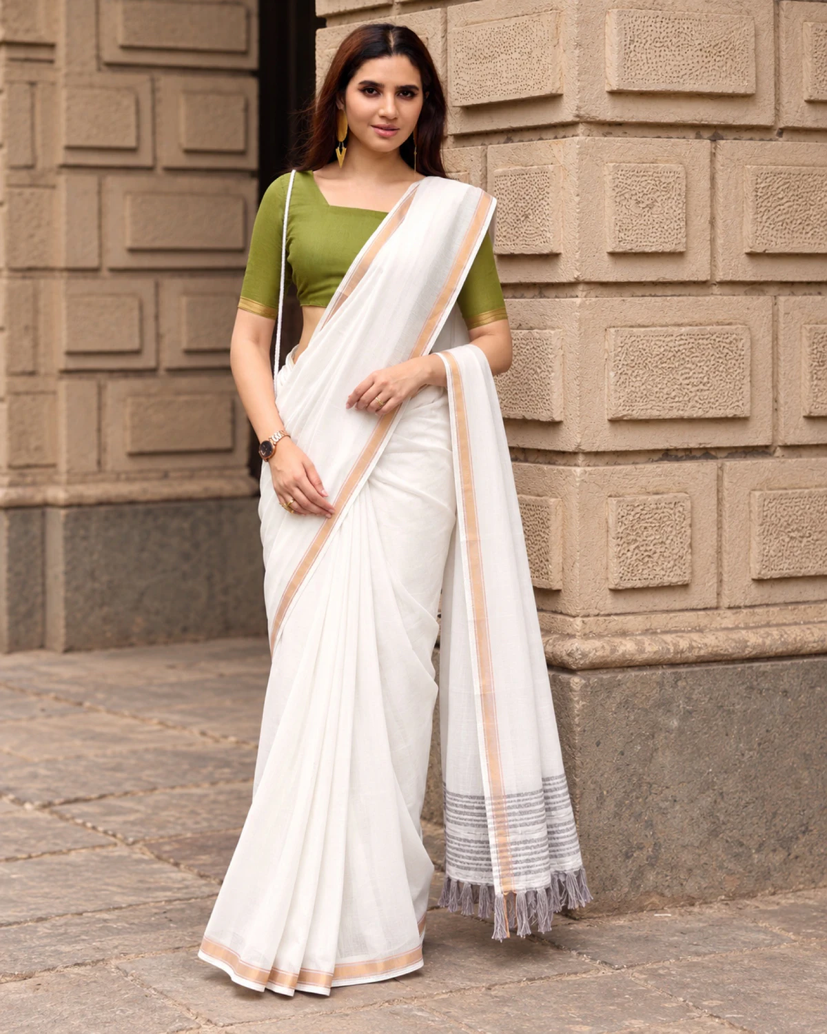 Woman standing in the white mul mul cotton saree, its grey-striped pallu falling in front
