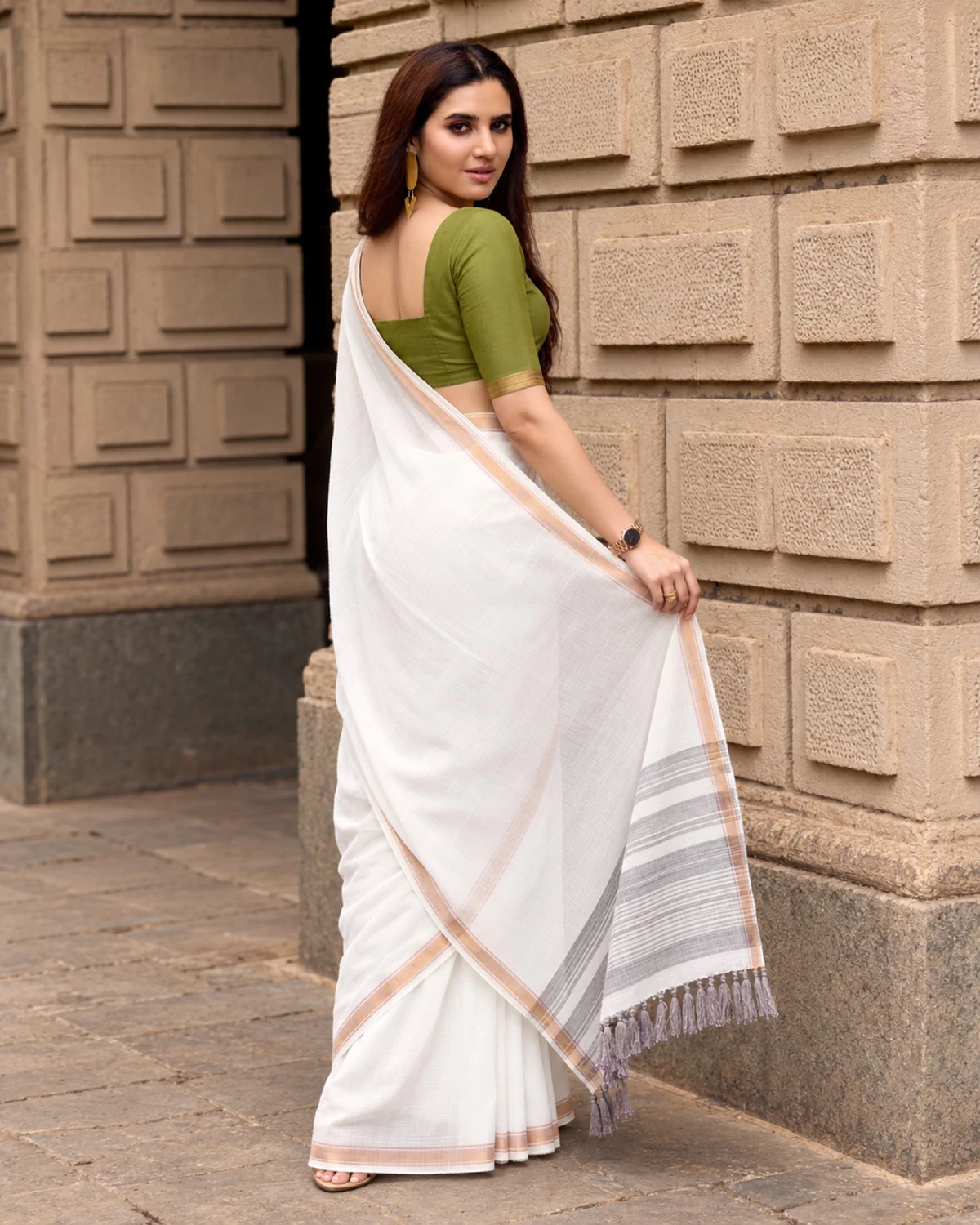 Back view of the white mul mul cotton saree, holding out its grey-striped pallu with tassels