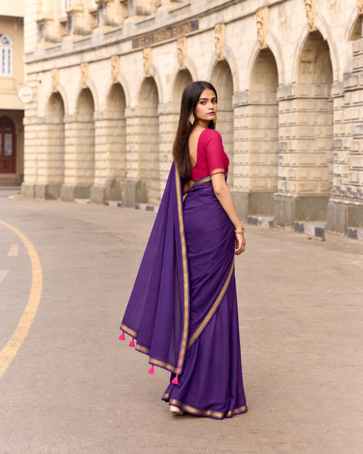 Back view of the purple mul mul cotton saree, its pallu with pink tassels held out to the side