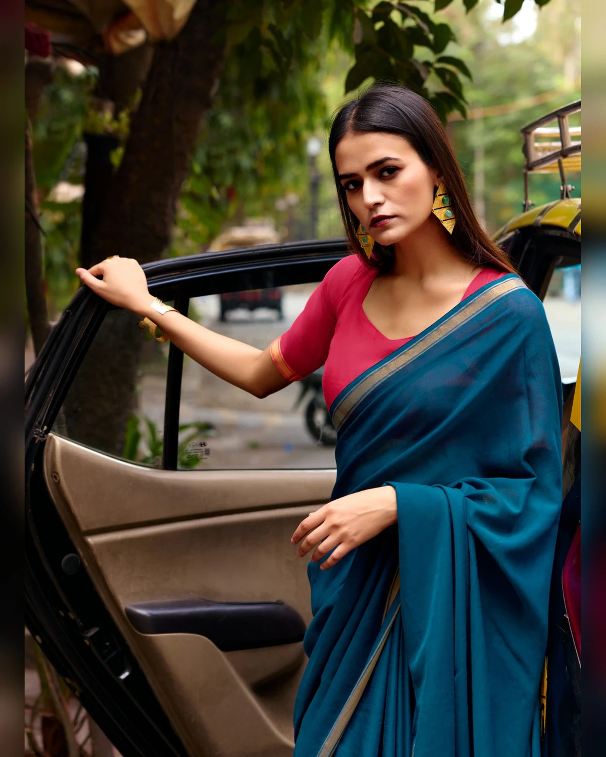 Woman in the teal blue mul mul cotton saree and pink blouse beside an open car door, seen from the waist up
