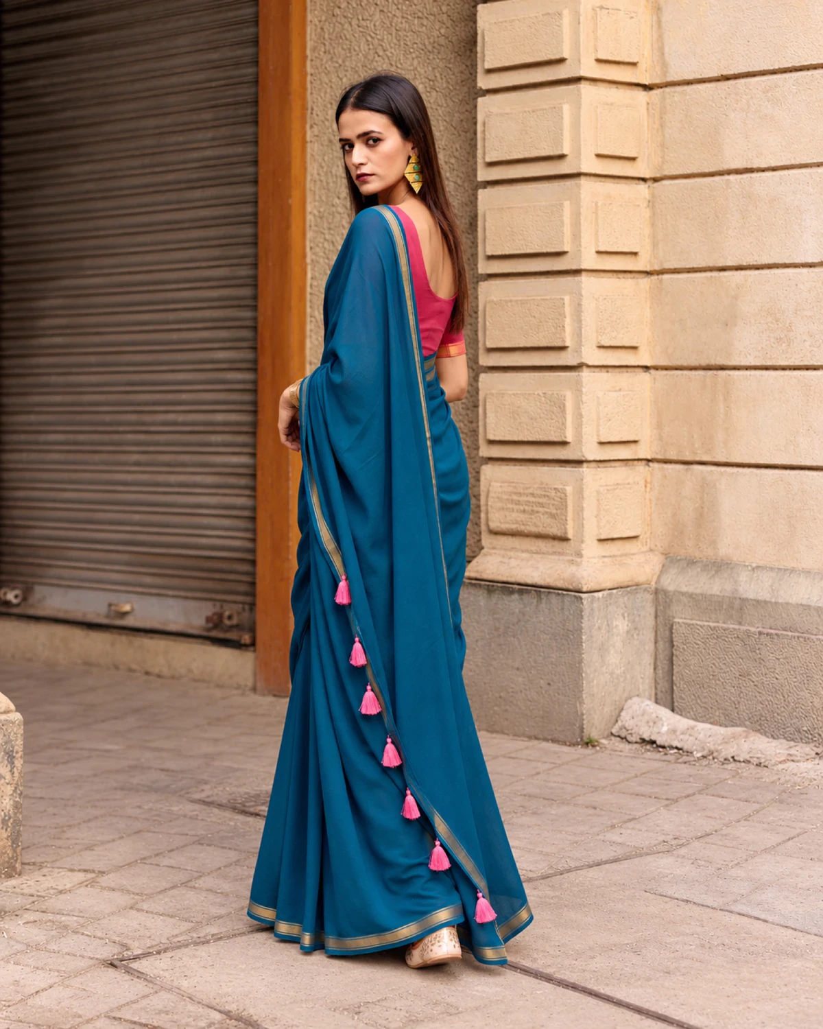 Back view of the teal blue mul mul cotton saree, pink tassels running down its pallu