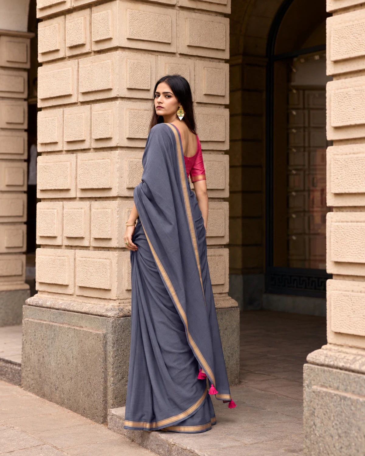 Back view of the grey mul mul cotton saree, its pallu with pink tassels falling down the back