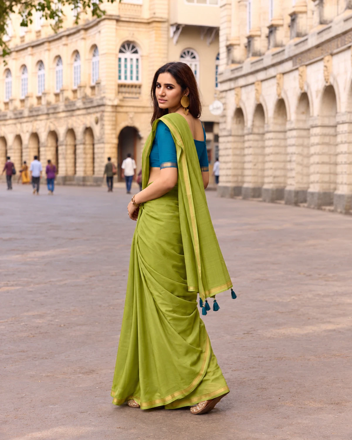 Back view of the olive green mul mul cotton saree, its pallu with teal tassels over her shoulder
