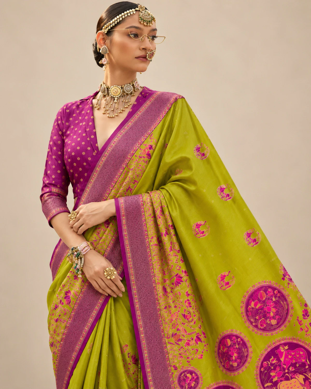 Close view of a woman in the lime green sigma silk saree, showing its purple border and printed pallu