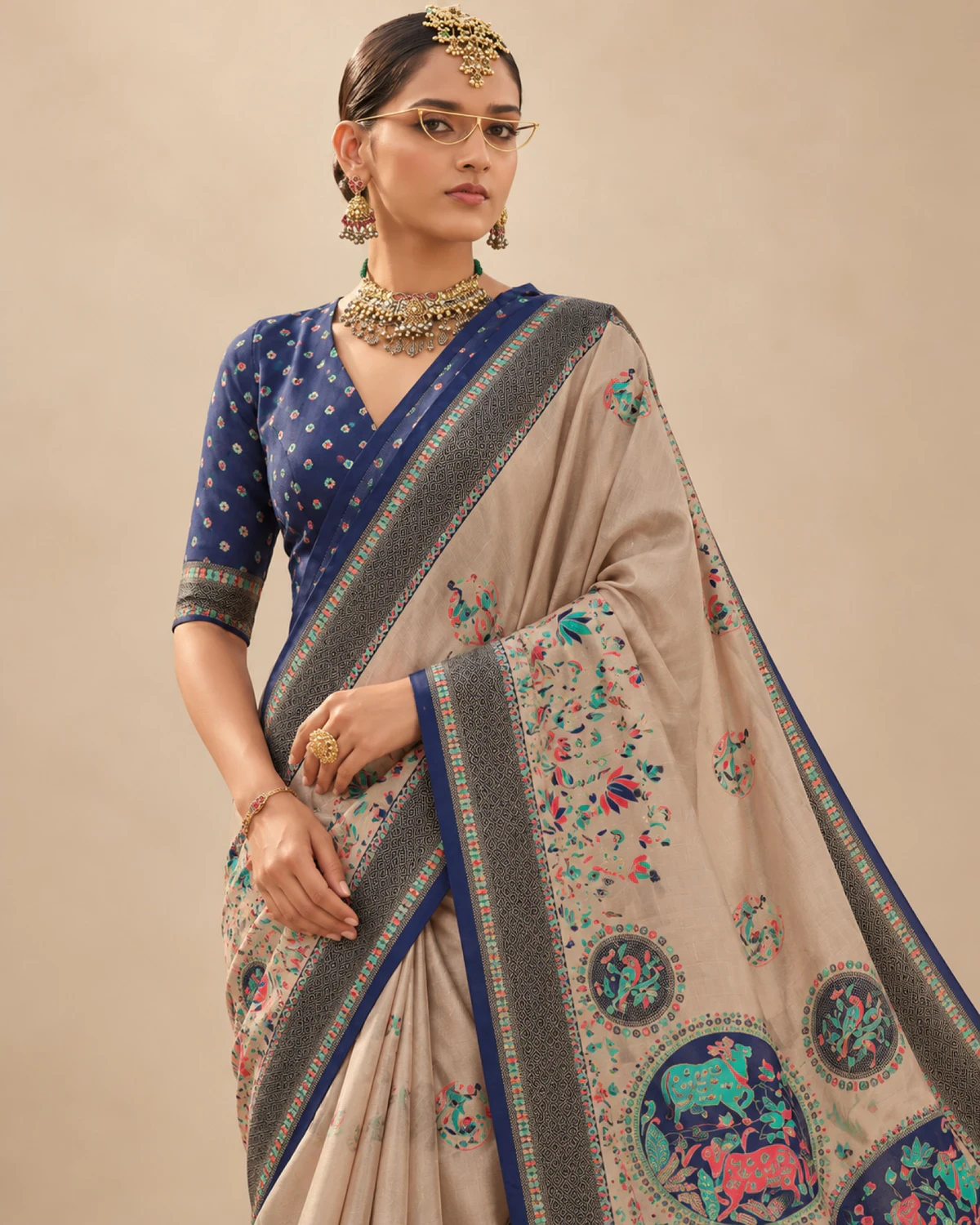 Close view of a woman in the beige sigma silk saree, showing its navy blue border and printed pallu