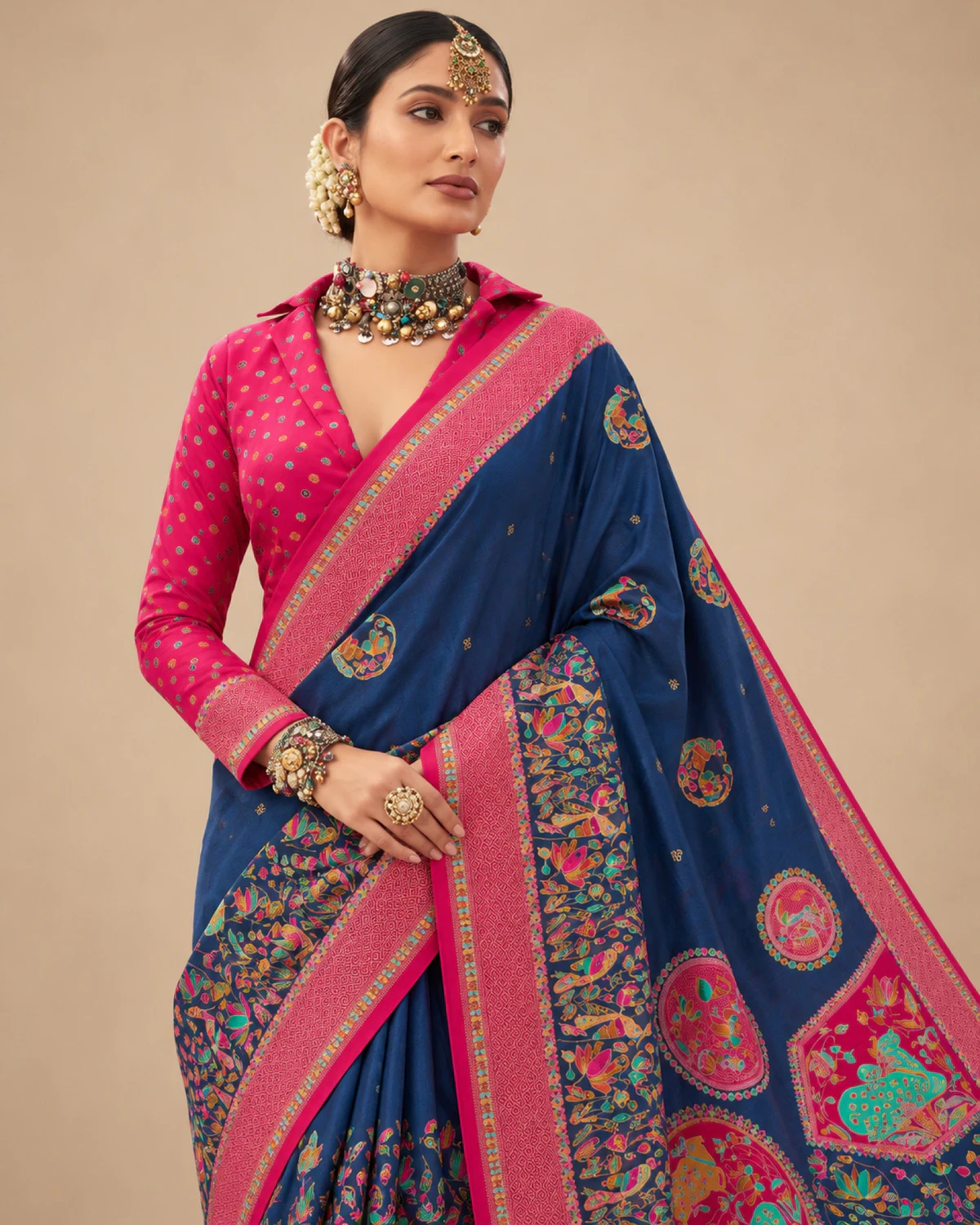 Close view of a woman in the navy blue sigma silk saree, showing its rani pink border and printed pallu