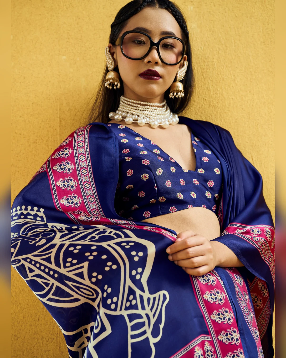 Close view of a woman in the navy blue saree, showing its rani pink Ajrakh border and printed blouse