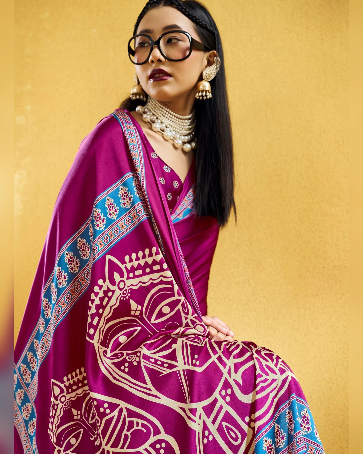Close view of a woman seated in the rani pink saree, its pallu of cream figures across her lap
