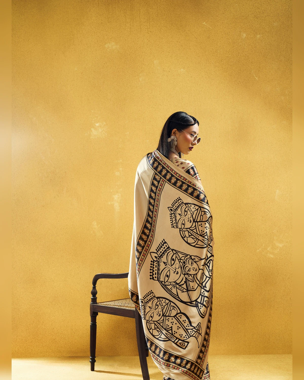Woman wrapped in the beige saree's pallu, showing its black line-drawn figures and Ajrakh border