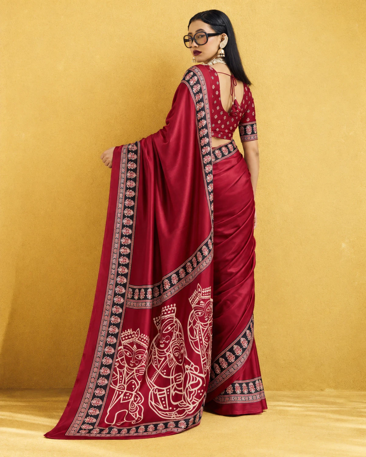 Back view of a woman in the red saree, its pallu of cream figures spread out behind her