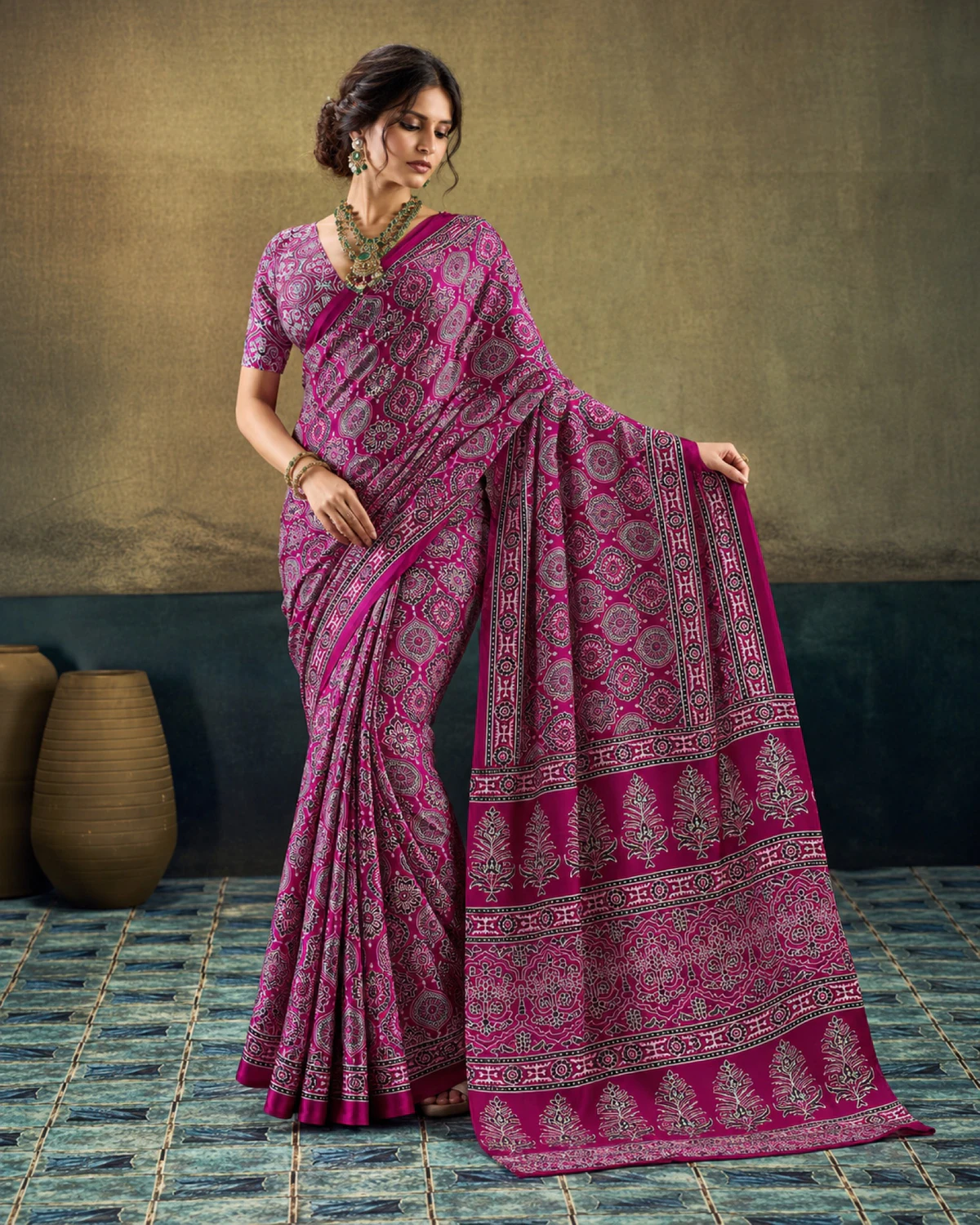 Woman holding out the plum saree's pallu to show its rows of tree-shaped butas