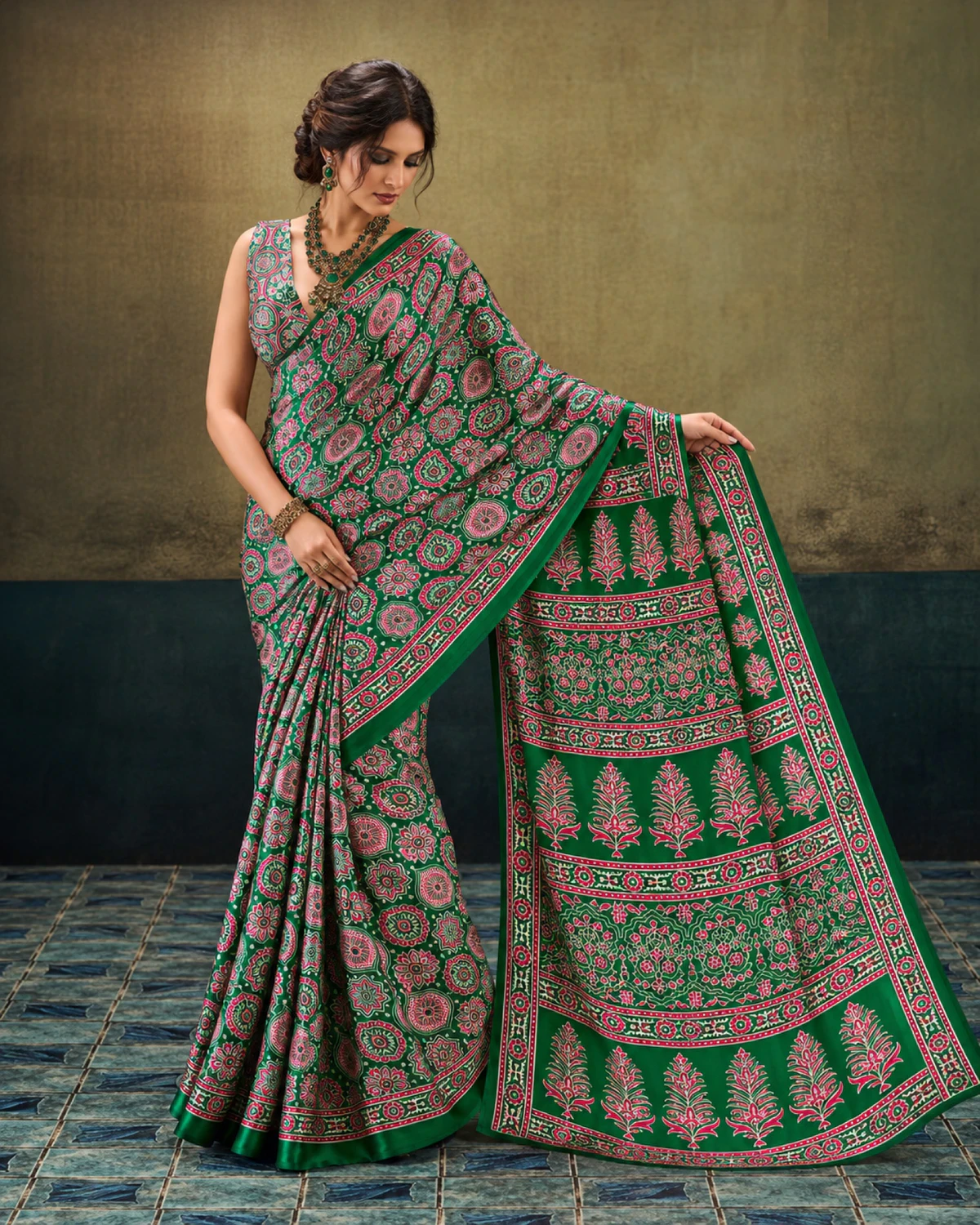 Woman holding out the emerald green saree's pallu to show its rows of tree-shaped butas