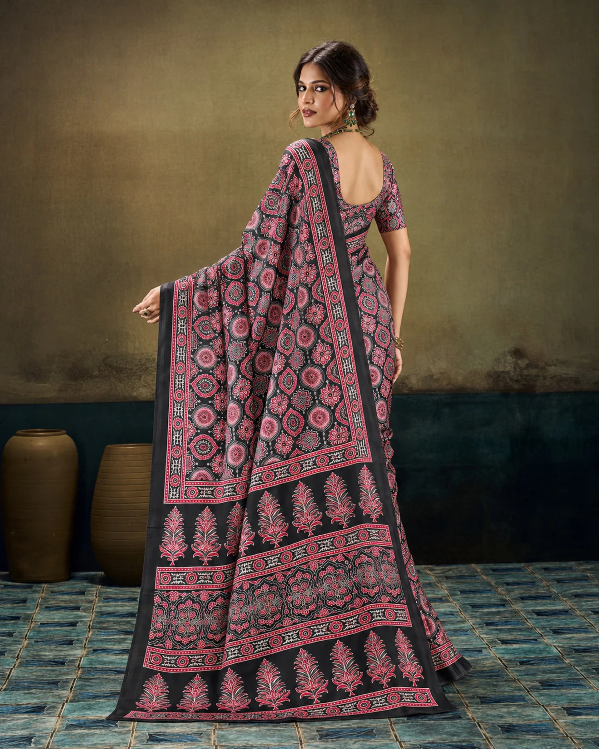 Back view of a woman in the black saree, its pallu of tree-shaped butas falling down the back