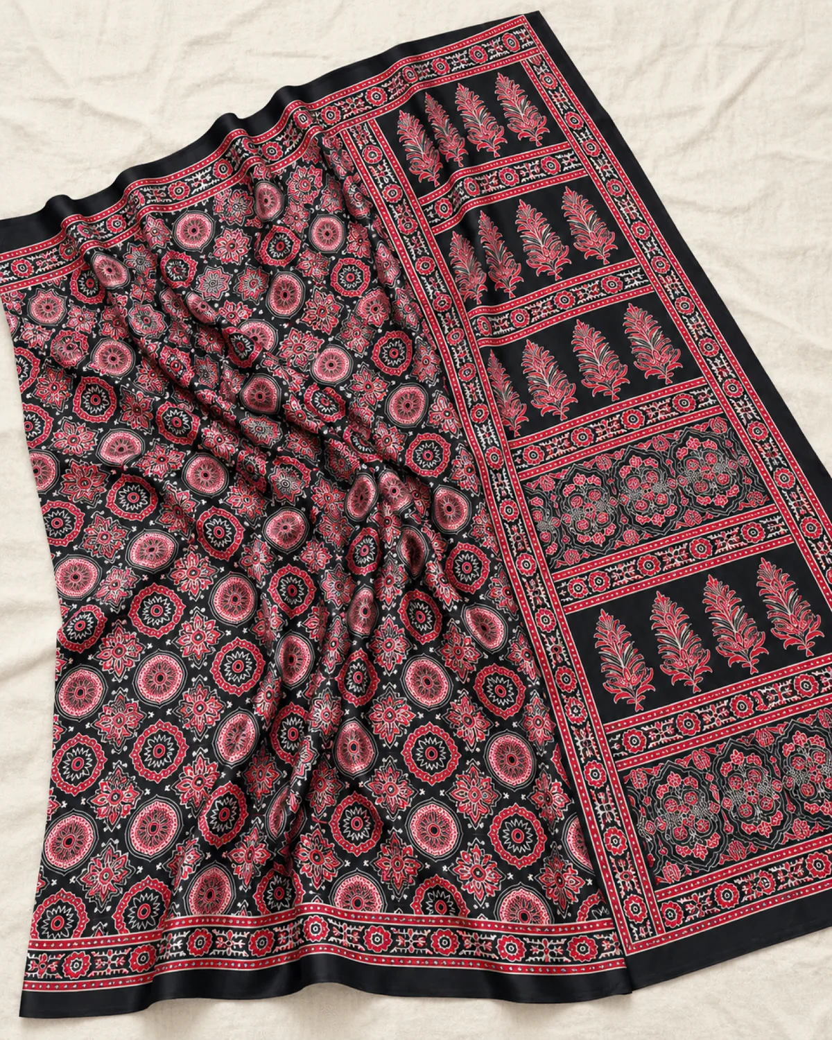 The black modal satin saree laid out flat, showing its pink and rose Ajrakh medallions and buta pallu