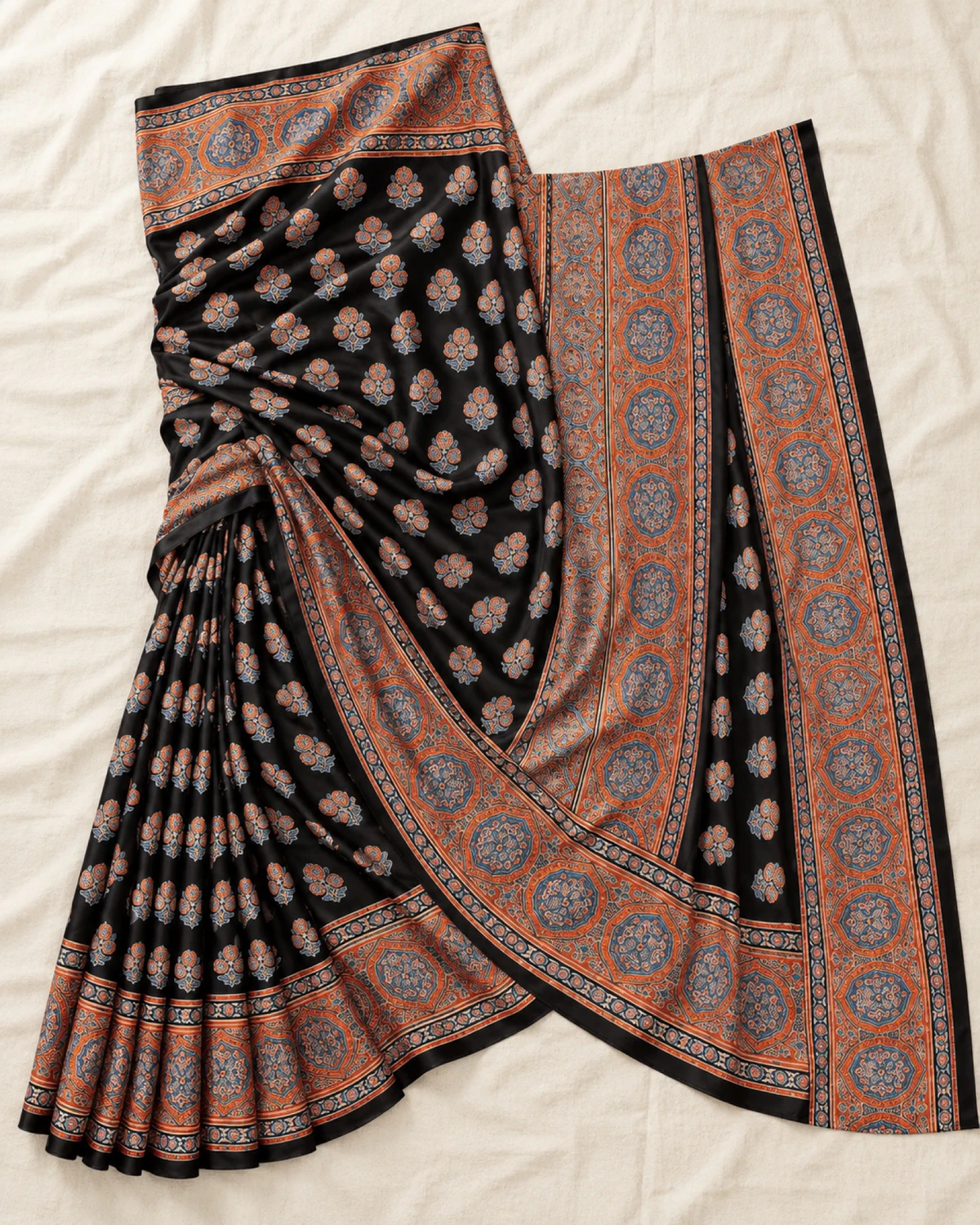 The black and rust modal satin saree laid out flat, showing its small butis and wide rust medallion border