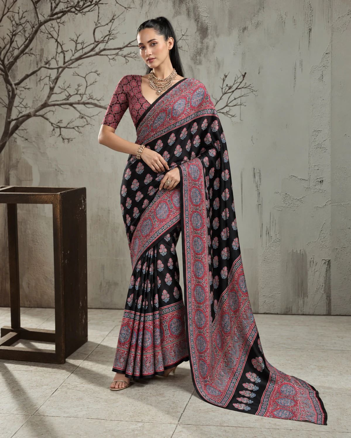 Woman in the black and red modal satin saree, its long pallu with red medallions falling to the floor
