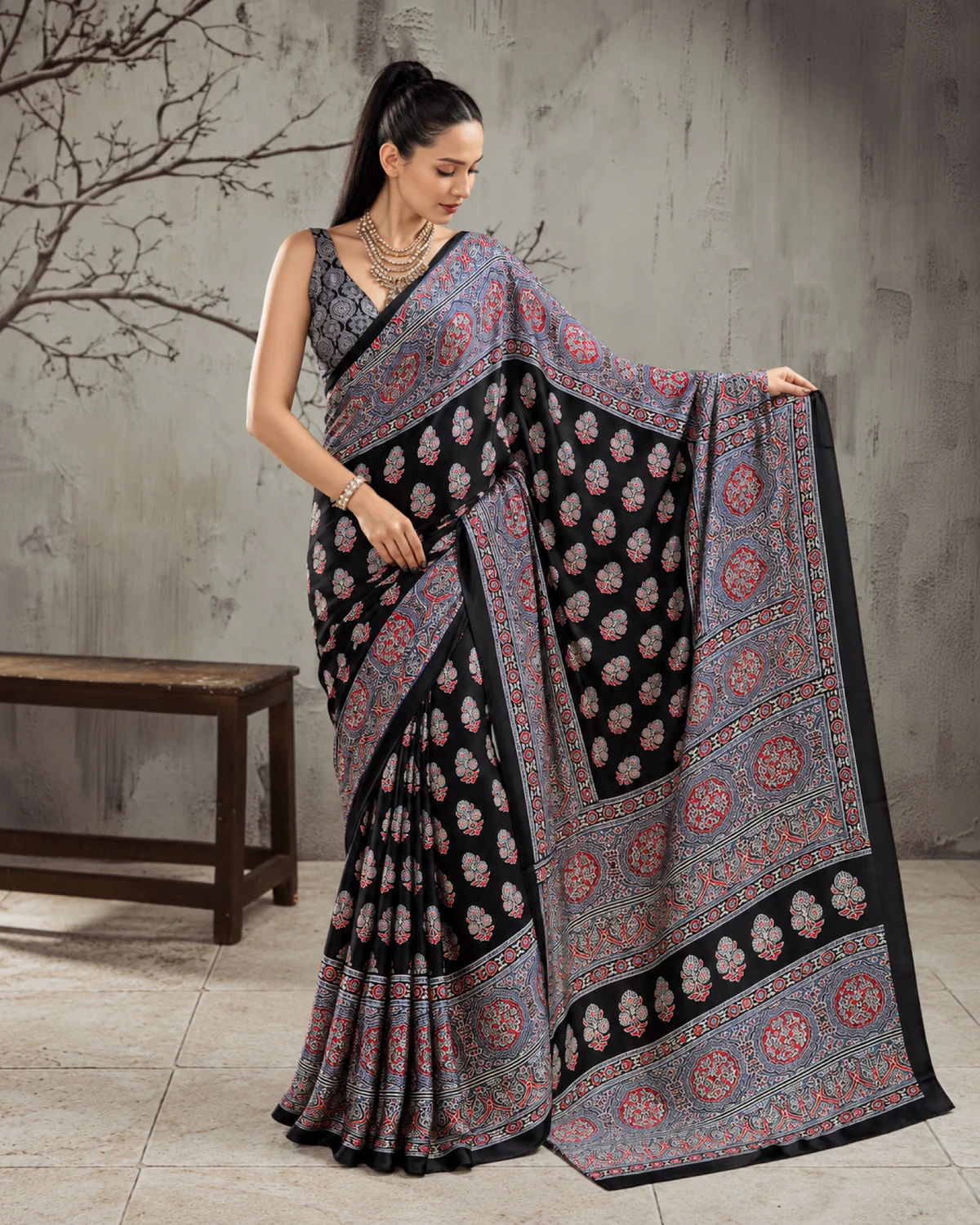 Woman holding out the black and grey saree's pallu to show its wide grey Ajrakh border