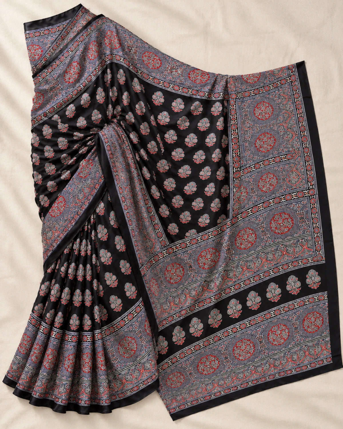 The black and grey modal satin saree laid out flat, showing its small butis and wide grey medallion border