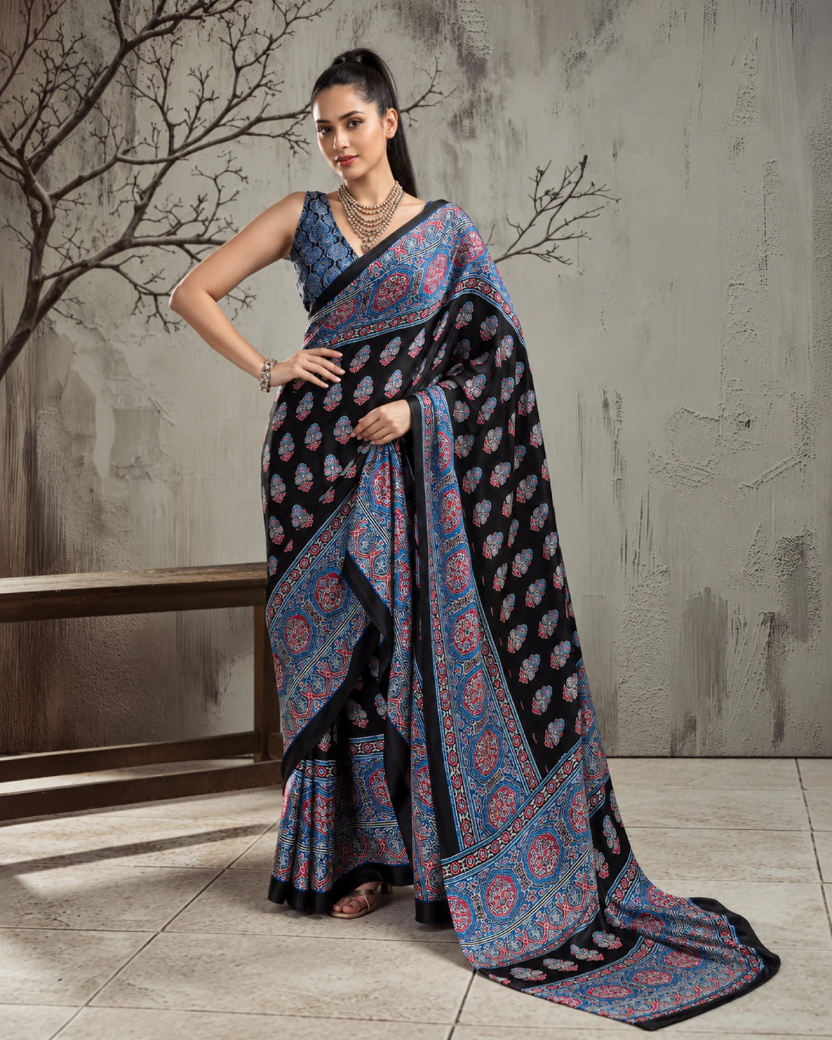 Woman in the black and blue modal satin saree, its long pallu with blue medallions falling to the floor