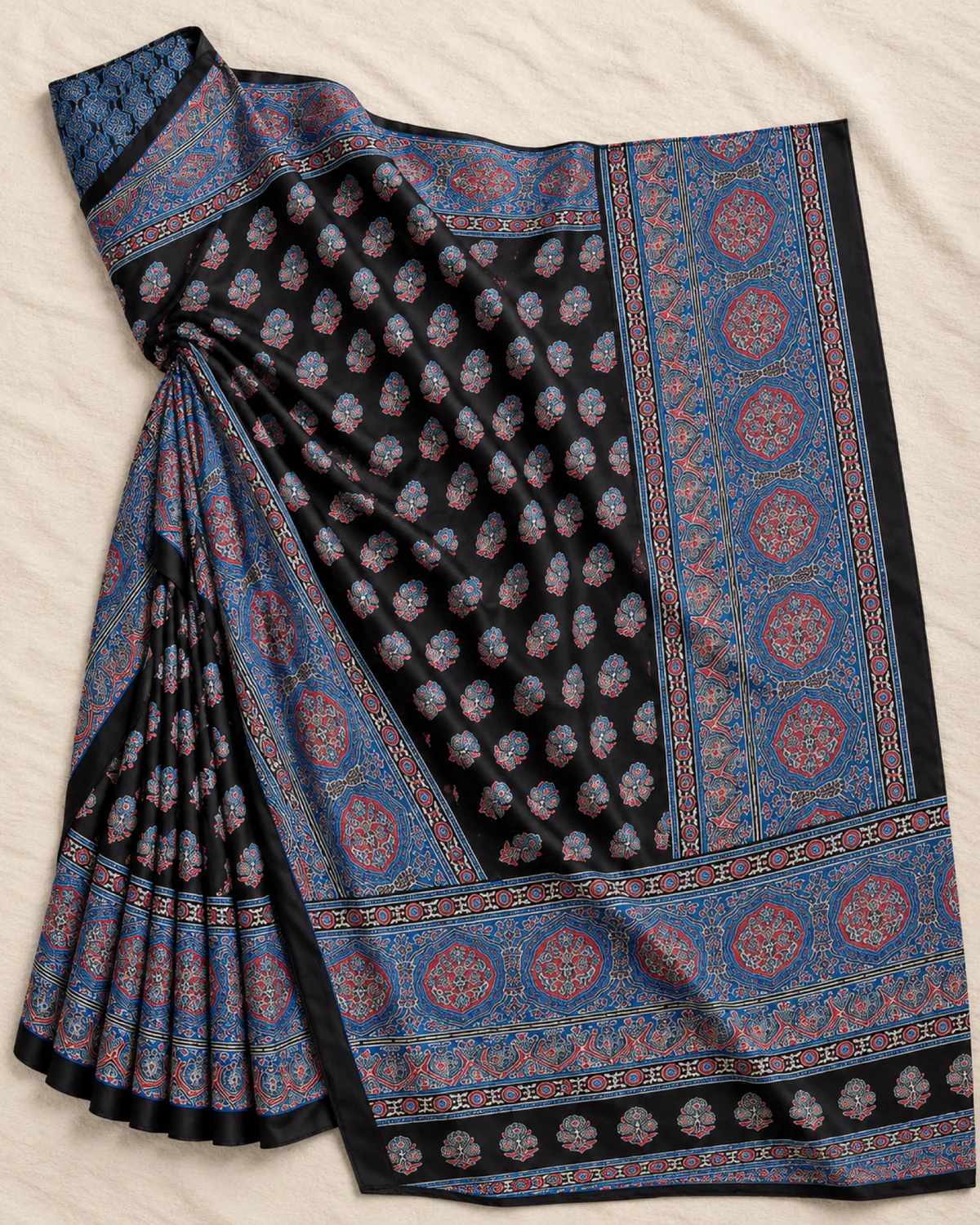 The black and blue modal satin saree laid out flat, showing its small butis and wide blue medallion border