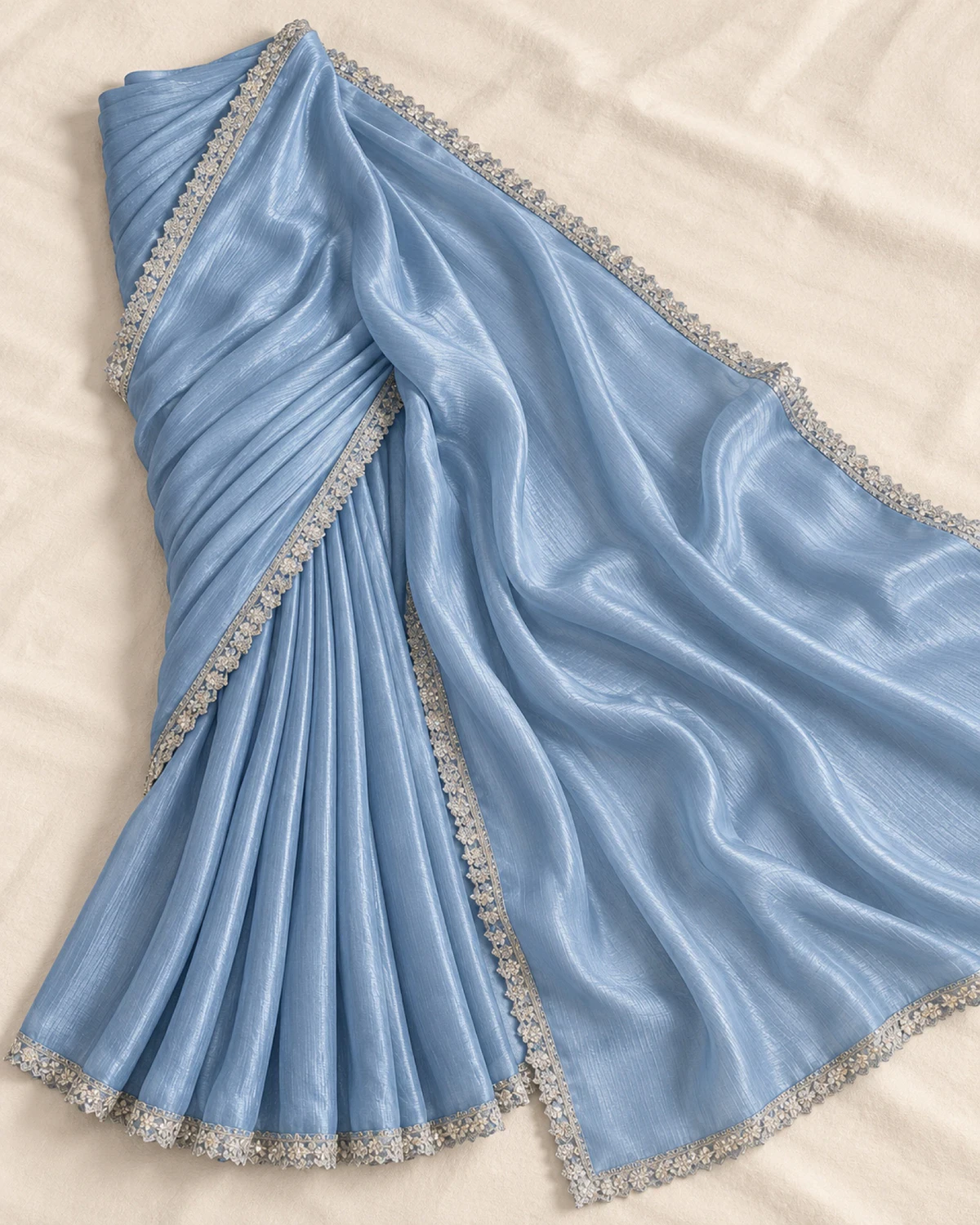 The powder blue shimmer chiffon saree laid flat on a cream cloth, showing its shimmer and silver border