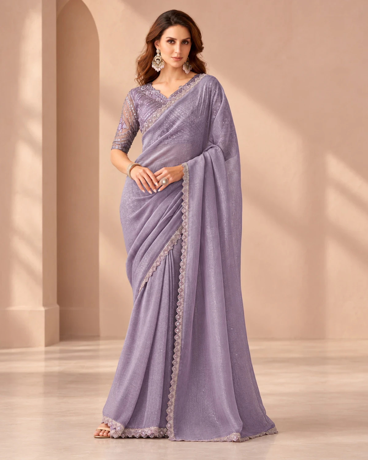 Woman wearing a lavender textured georgette saree with a scalloped silver-toned border, standing in a softly lit peach room